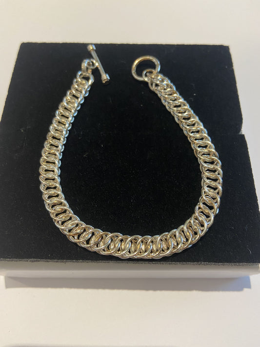 Silver Bracelet Cleverly entwined silver hoops knitted together to lie flat